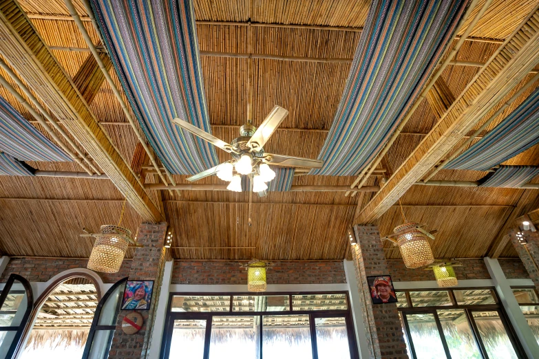 a living room filled with furniture and a ceiling fan, by Carey Morris, unsplash, art nouveau, bamboo huts, cables hanging from ceiling, restaurant menu photo, avatar image