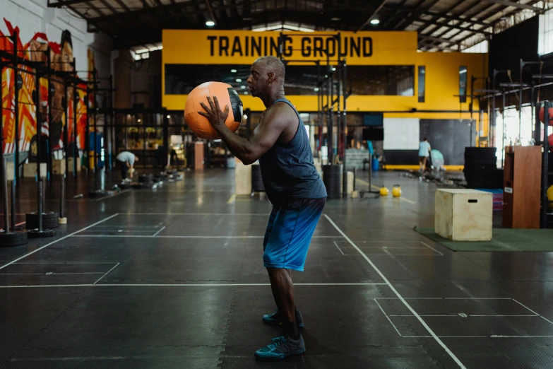 a man holding a basketball in a gym, by Bernardino Mei, dribble, athletic crossfit build, black and yellow scheme, ground - level medium shot, malaysian