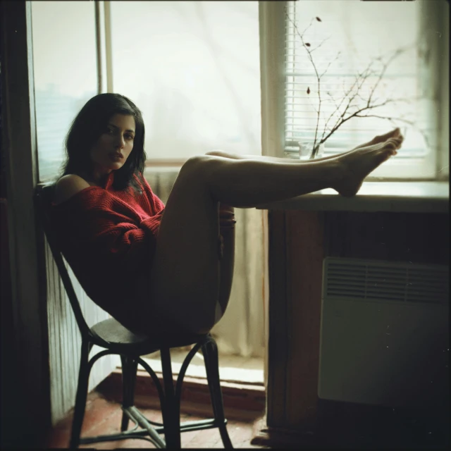 a woman sitting in a chair in front of a window, a polaroid photo, inspired by Elsa Bleda, art photography, a woman wearing red high heels, alexey egorov, medium format, sittin