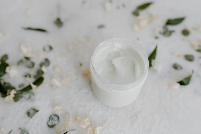 a close up of a jar of cream on a table, by Emma Andijewska, trending on pexels, renaissance, sea foam, botanical, background image, white