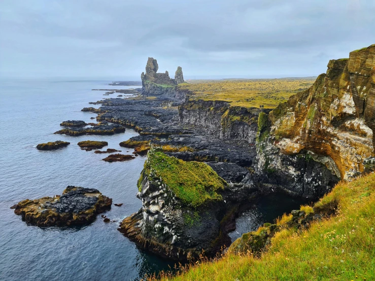 a large body of water sitting on top of a lush green hillside, by Þórarinn B. Þorláksson, pexels contest winner, romanticism, black domes and spires, cliffside ocean scene, lava rivers, conde nast traveler photo