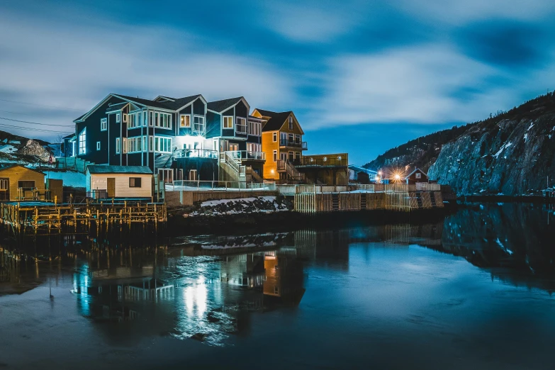 a large building sitting next to a body of water, by Ryan Pancoast, pexels contest winner, picton blue, taverns nighttime lifestyle, fishing village, slide show