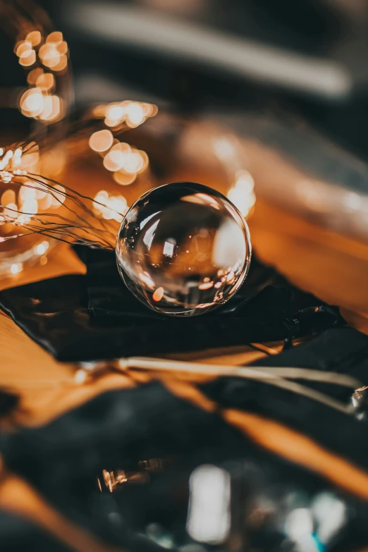 a glass ball sitting on top of a wooden table, trending on pexels, magical realism, string lights, drops around, flatlay, with sparking circuits