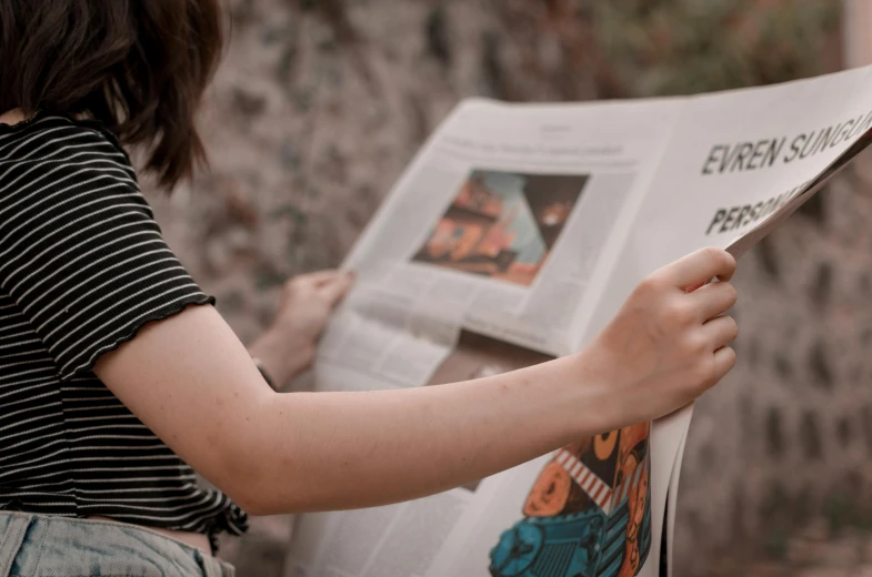 a woman reading a newspaper in front of a stone wall, a picture, pexels contest winner, little kid, holding an epée, avatar image, newspaper article
