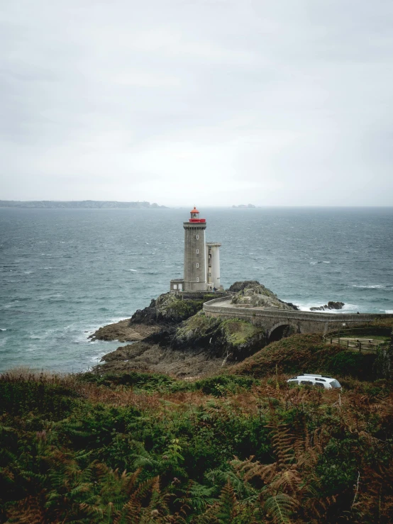 a lighthouse sitting on top of a cliff next to the ocean, breton cap, slide show, gloomy skies, gif