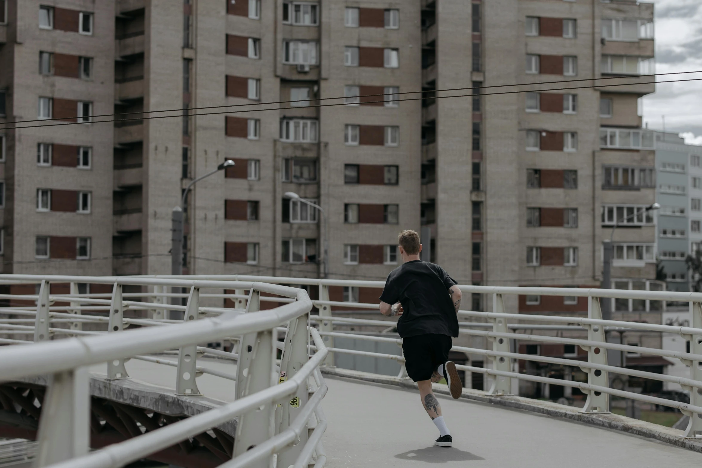 a man riding a skateboard across a bridge, pexels contest winner, city rooftop, background image, people running, local gym