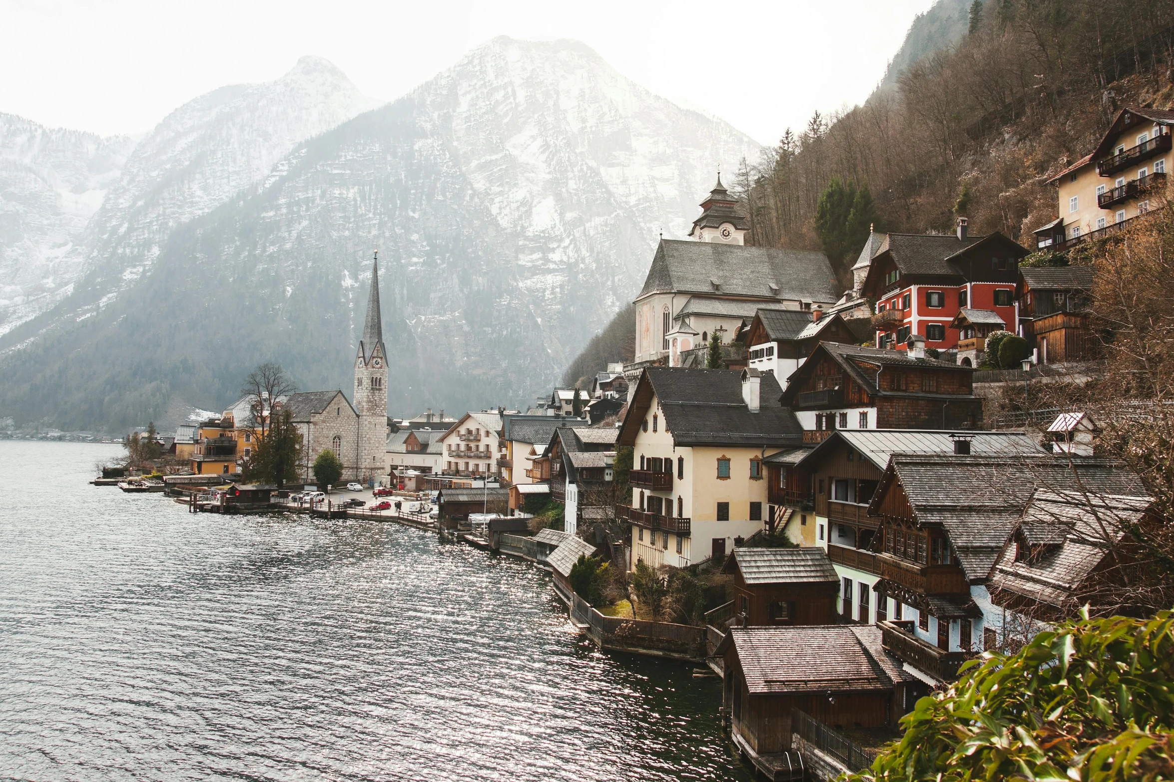 a town next to a body of water with mountains in the background, pexels contest winner, vintage european folk art, grey, conde nast traveler photo, a cozy