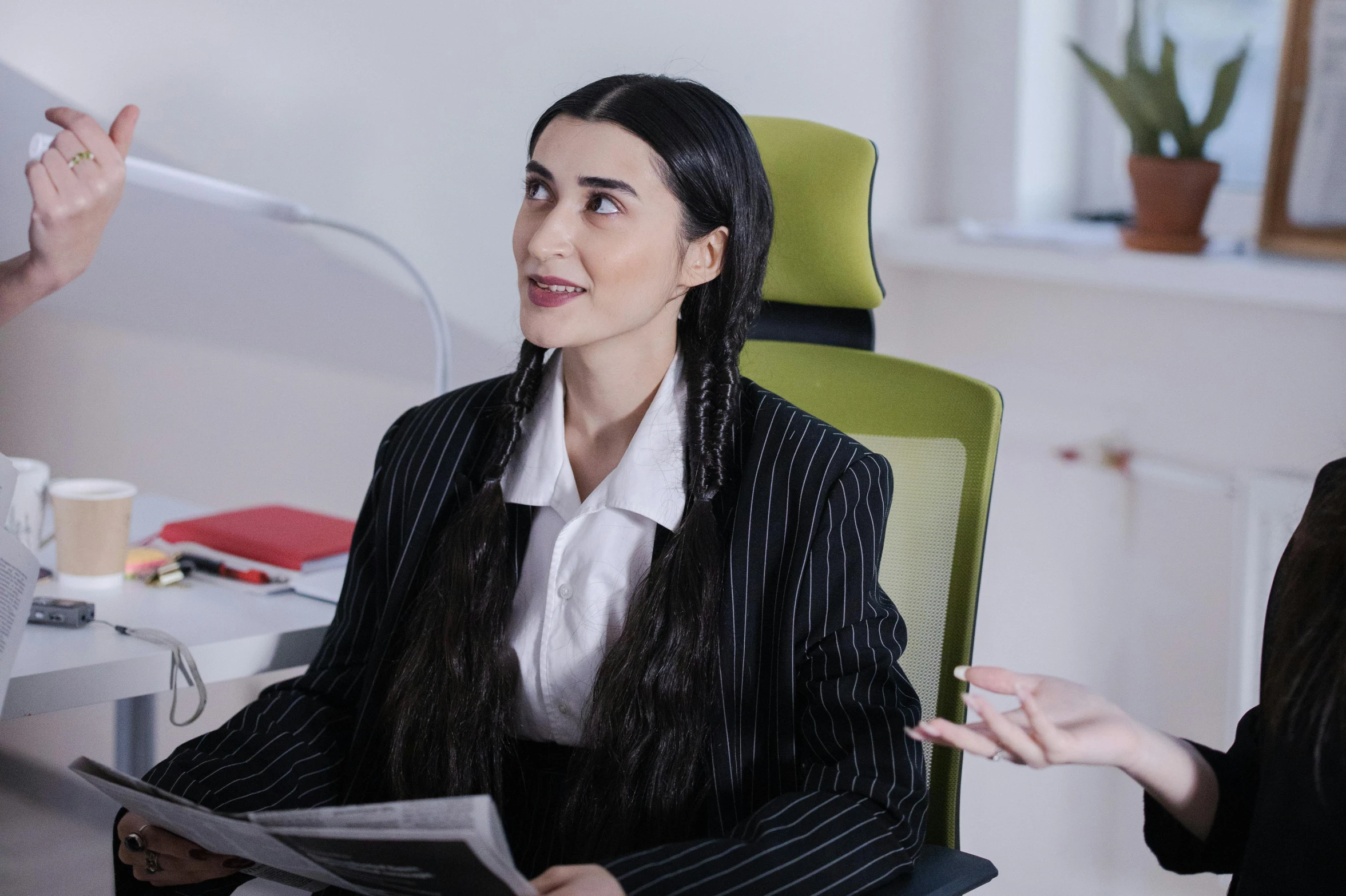 a woman sitting in a chair talking to another woman, a colorized photo, inspired by Marina Abramović, trending on pexels, hurufiyya, sitting behind desk, avatar image, office clothes, as wednesday addams