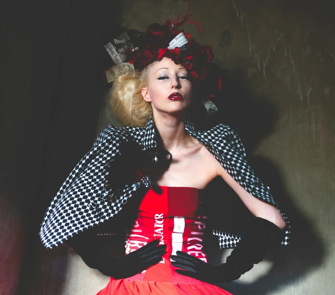 a woman in a red dress and black and white jacket, inspired by Cecil Beaton, kitsch movement, mesh headdress, promotional photo, red door blonde, vests and corsets