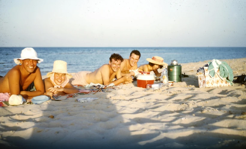 a group of people laying on top of a sandy beach, a colorized photo, bauhaus, 1 9 5 0 s americana tourism, having a snack, smiling for the camera, profile picture 1024px