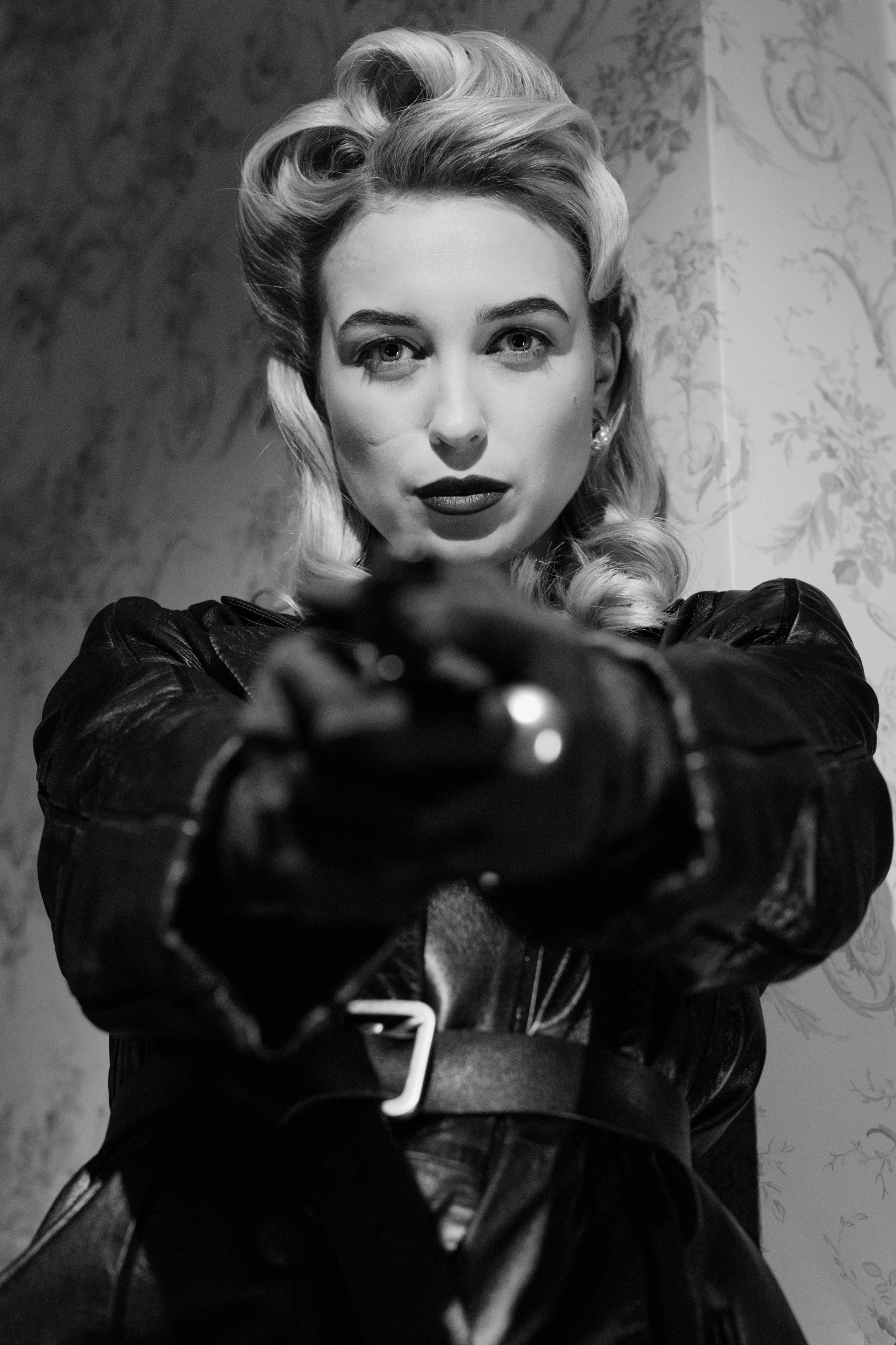 a black and white photo of a woman holding a gun, a black and white photo, inspired by Evaline Ness, reddit, black canary, black leahter gloves, sydney sweeney, rockabilly