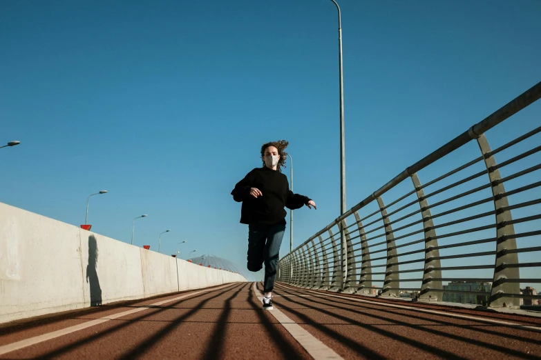 a man running across a bridge on a sunny day, by Nathalie Rattner, pexels contest winner, realism, teenage girl, cinematic lut, running pose, low-key