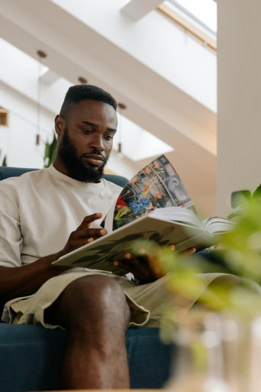 a man sitting on a couch reading a book, pexels contest winner, afrofuturism, casually dressed, jaylen brown, gif, magazines