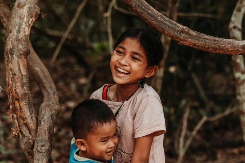 a couple of kids standing next to each other, pexels contest winner, sumatraism, both laughing, avatar image, indigenous, in a tree