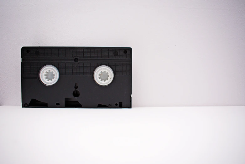 a black cassette sitting on top of a white table, wide screen format, promo image, unknown technology, lossless