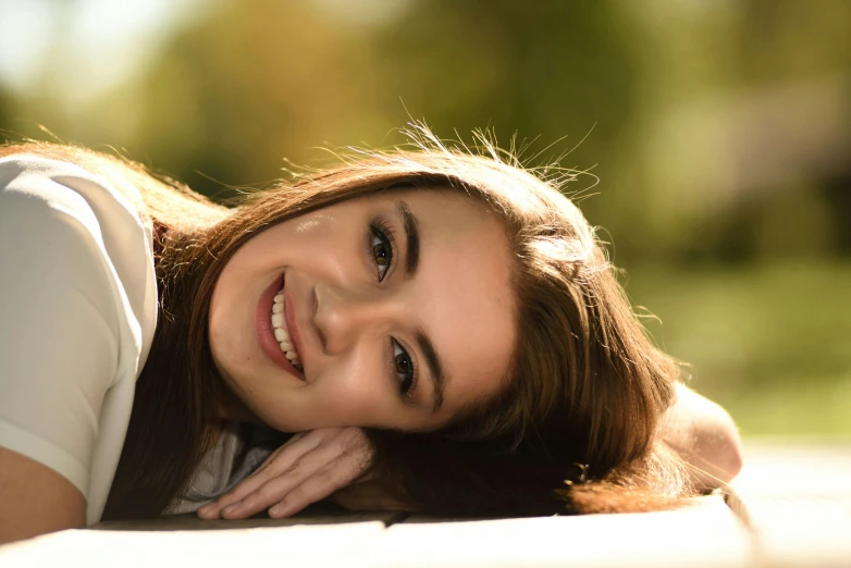 a beautiful young woman laying on top of a wooden bench, pexels contest winner, photorealism, pretty smile, portrait sophie mudd, backlit beautiful face, girl with brown hair