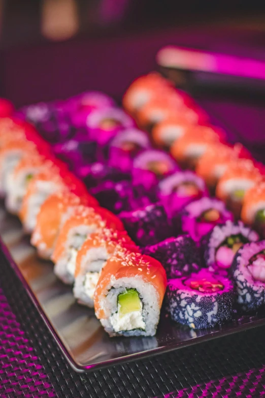 a plate of sushi rolls on a table, bright pink purple lights, sea of parfait, retro stylised, upclose