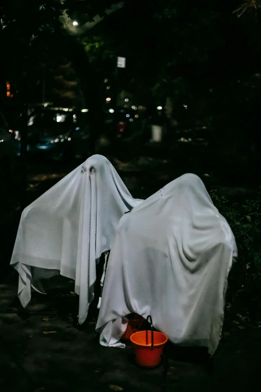 a couple of white cloths sitting on top of a sidewalk, ghouls, shroud, 2019 trending photo, unsplash photo contest winner