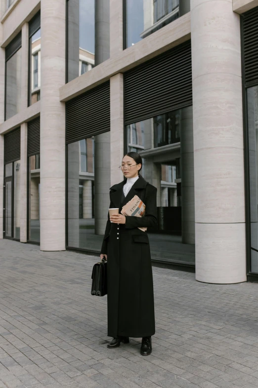 a woman standing on a sidewalk in front of a building, lawyer clothing, wearing modern gothic clothes, orthodox, lawyer