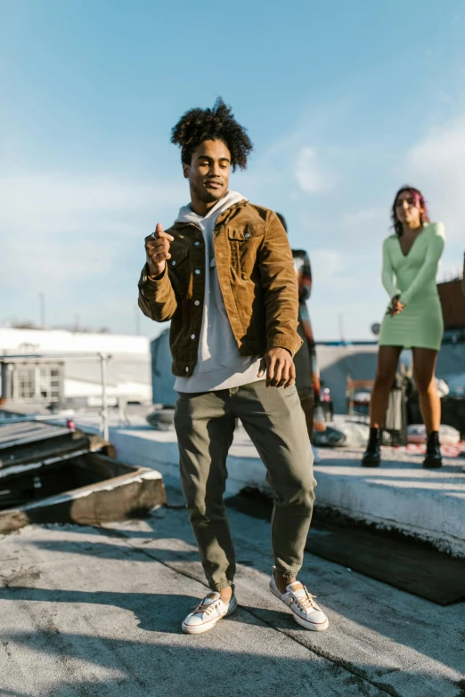 a group of people standing on top of a roof, an album cover, trending on pexels, green and brown clothes, black man with afro hair, looking to the side off camera, man standing in defensive pose