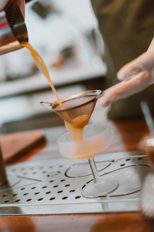 a person pouring a drink into a glass, inspired by Carlo Martini, unsplash, aussie baristas, caramel, zoomed in, flawless structure