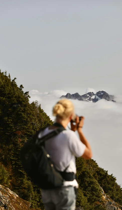 a man standing on top of a mountain taking a picture, by Jessie Algie, standing on a cloud, over the shoulder view, today\'s featured photograph 4k, oregon