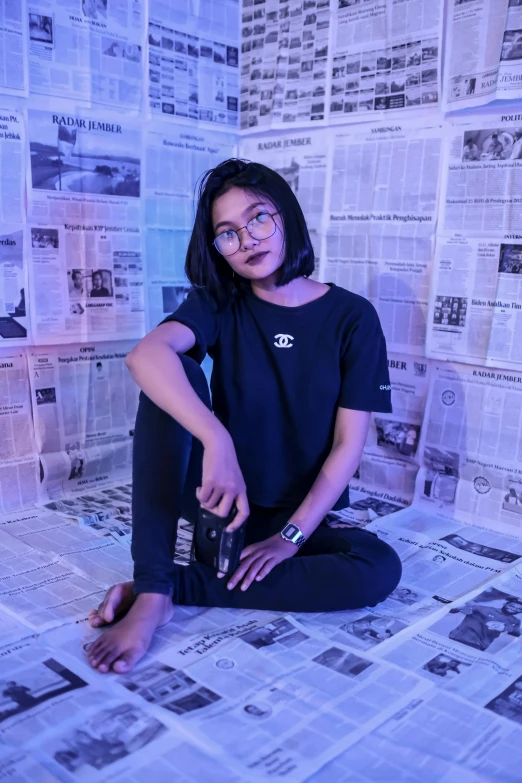 a woman sitting on the floor in front of a wall of newspapers, inspired by Bernardino Mei, unsplash contest winner, wearing a black tshirt, ☁🌪🌙👩🏾, nivanh chanthara, hypebeast