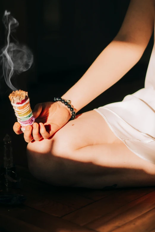 a woman sitting on the floor with a cigarette in her hand, a colorized photo, trending on unsplash, renaissance, incense, long trunk holding a wand, chakras, stacked image