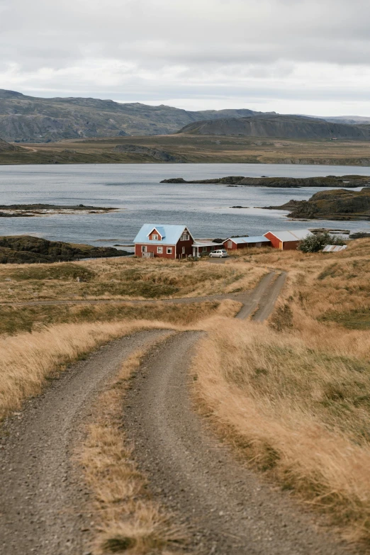 a dirt road next to a body of water, by Hallsteinn Sigurðsson, pexels contest winner, dau-al-set, next to a farm house and a barn, two medium sized islands, gray and orange colours, movie photo