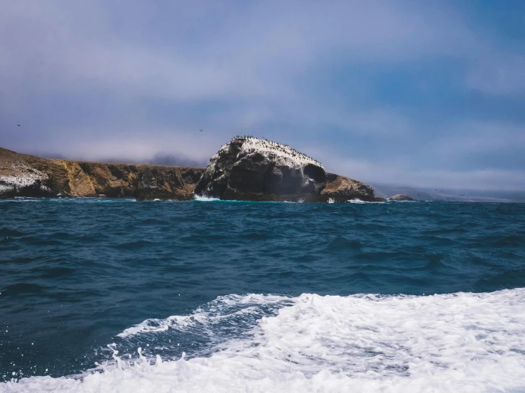 a large rock in the middle of a body of water, a photo, pch, fan favorite, two medium sized islands, high quality image