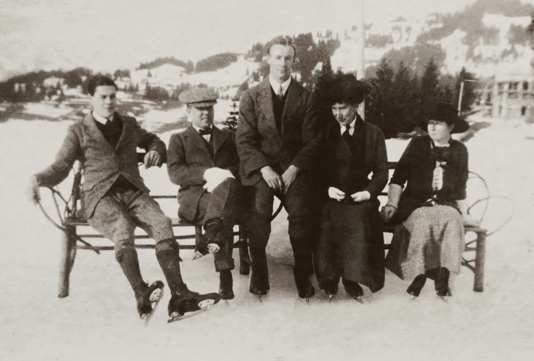 a group of men sitting on a bench in the snow, a black and white photo, art nouveau, with mountains in background, promo image, the bauhaus, family photo