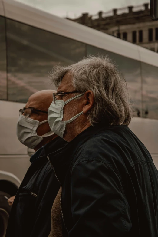 two people wearing face masks in front of a bus, by Adam Marczyński, pexels contest winner, happening, old man, plain background, profile image, plague