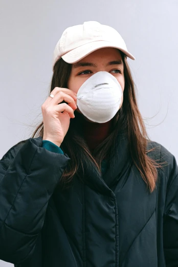 a woman wearing a face mask while talking on a cell phone, by Nina Hamnett, trending on pexels, renaissance, wearing a baseball hat, hailee steinfeld, smog, on grey background