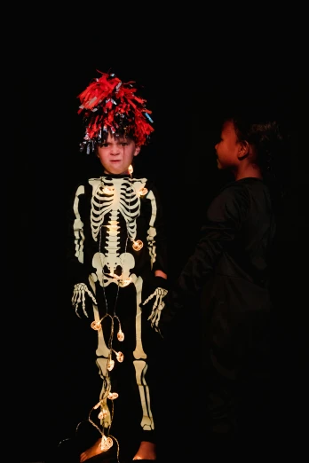 a couple of kids standing next to each other on a stage, pexels contest winner, vanitas, dress made of bones, on a black background, slide show, in costume
