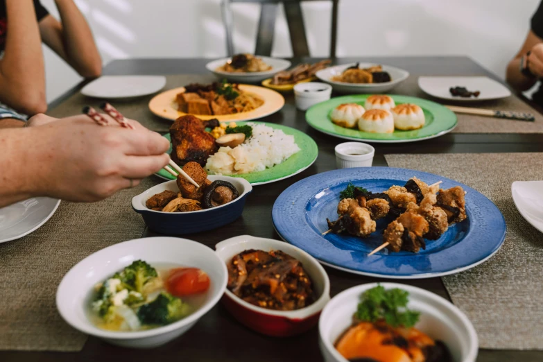 a group of people sitting at a table with plates of food, pexels contest winner, mingei, background image, gemma chen, about to consume you, te pae