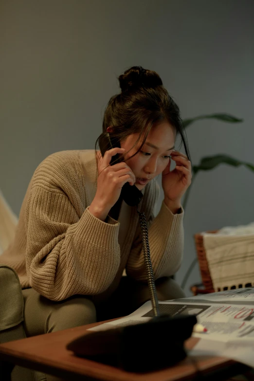 a woman sitting on a couch talking on a phone, by Jang Seung-eop, trending on pexels, realism, on a desk, production still, warm coloured, casually dressed