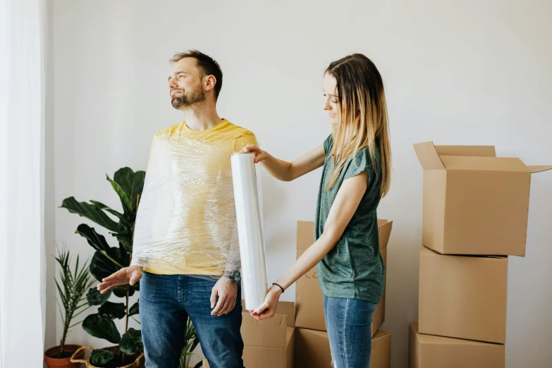 a man and a woman standing in a room with moving boxes, cracked plastic wrap, avatar image, listing image, woman holding another woman