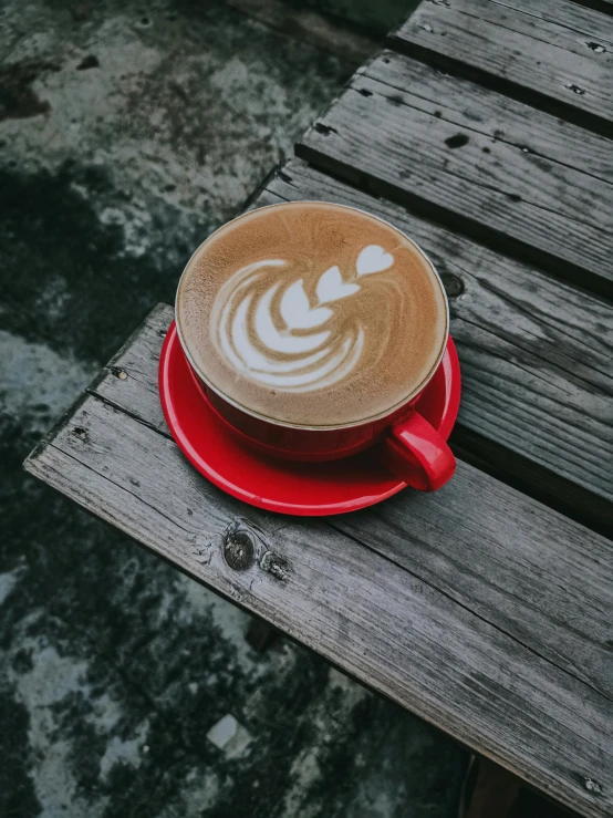 a cup of coffee sitting on top of a wooden table, by Austin English, pexels contest winner, red and grey only, milk and mocha style, at the waterside, thumbnail