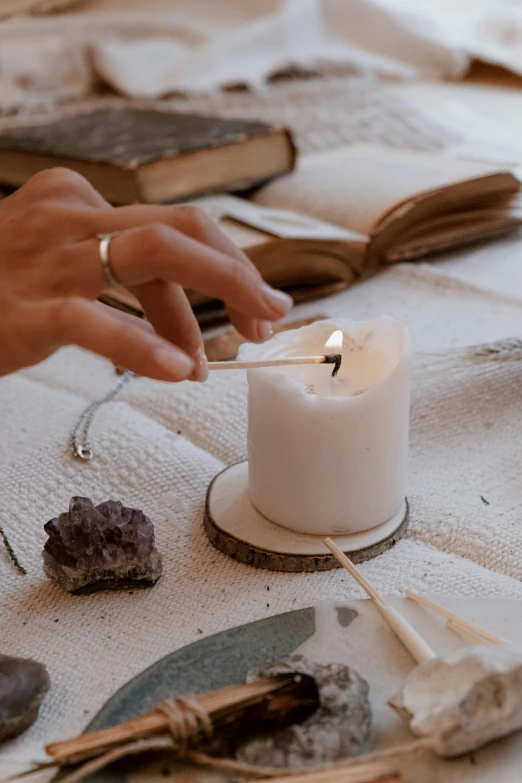 a person lighting a candle on a table, inspired by Elsa Bleda, trending on pexels, natural materials, white witch, flat lay, profile image