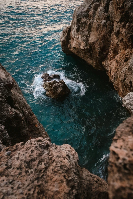 a man standing on top of a cliff next to the ocean, by Matija Jama, pexels contest winner, pools of water, deep crevices of stone, middle close up composition, croatian coastline