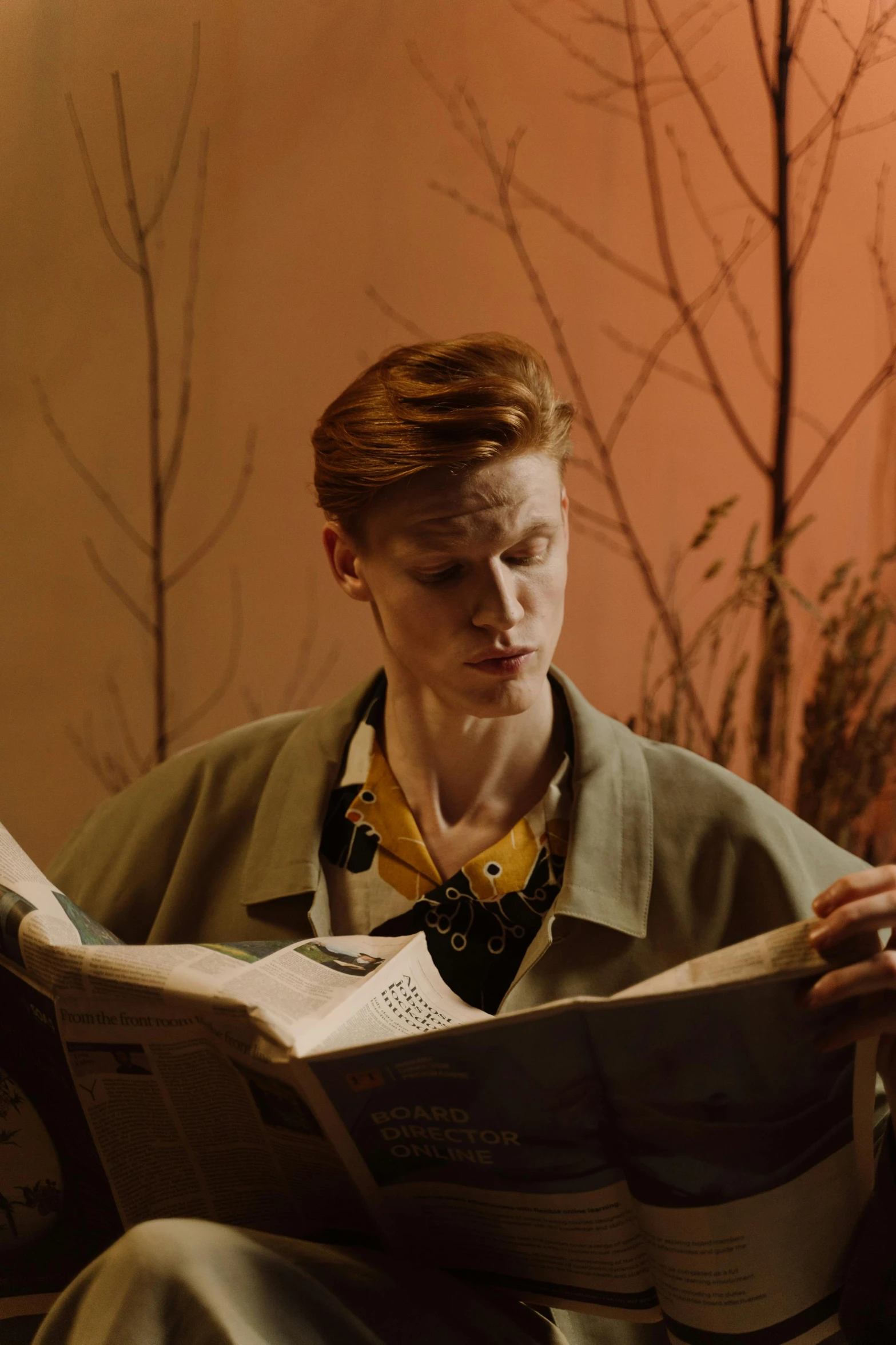 a man sitting on a couch reading a book, an album cover, fantastic realism, portrait tilda swinton, still from a music video, red haired teen boy, 15081959 21121991 01012000 4k