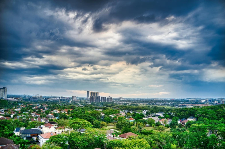 a view of a city from the top of a hill, by Basuki Abdullah, pexels contest winner, hurricane stromy clouds, panoramic, over the tree tops, colombo sri lanka cityscape