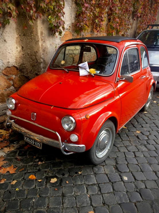 a small red car parked on a cobblestone street, the fall of rome, but very good looking”, super adorable, up close