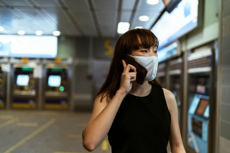 a woman wearing a face mask while talking on a cell phone, by Julia Pishtar, pexels contest winner, rings asuka iwakura station game, white man with black fabric mask, asian girl, ready to model