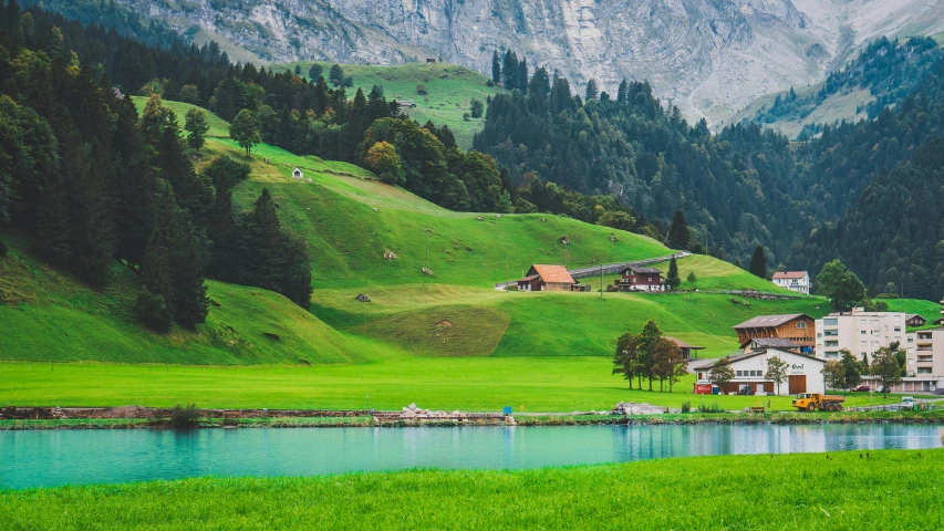 a group of houses sitting on top of a lush green hillside, by Sebastian Spreng, pexels contest winner, beautiful lake, tall acid green grass field, swiss, conde nast traveler photo