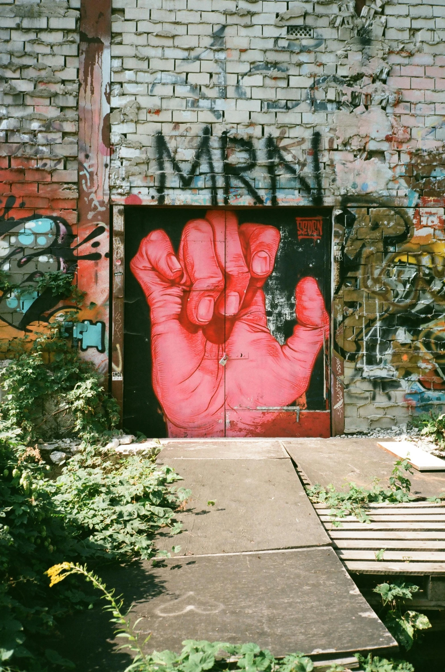 a red hand painted on the side of a building, graffiti art, by Mór Than, unsplash, street art, berlin 1 9 8 2, pink door, raised fist, beautiful surroundings