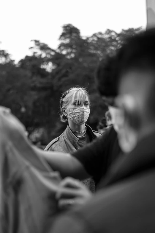 a black and white photo of a woman wearing a face mask, by Giorgio Cavallon, pexels contest winner, in front of a large crowd, hands shielding face, behind the scenes, ((portrait))