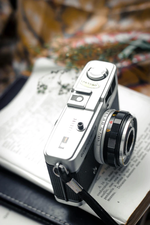 a camera sitting on top of an open book, fuji provia, nostalgic and euphoric, with laser-like focus, on a white table