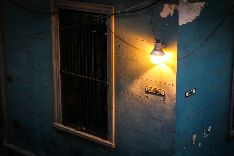 a light that is on the side of a building, an album cover, inspired by Elsa Bleda, unsplash, location ( favela ), indoor lighting, porches, blue light