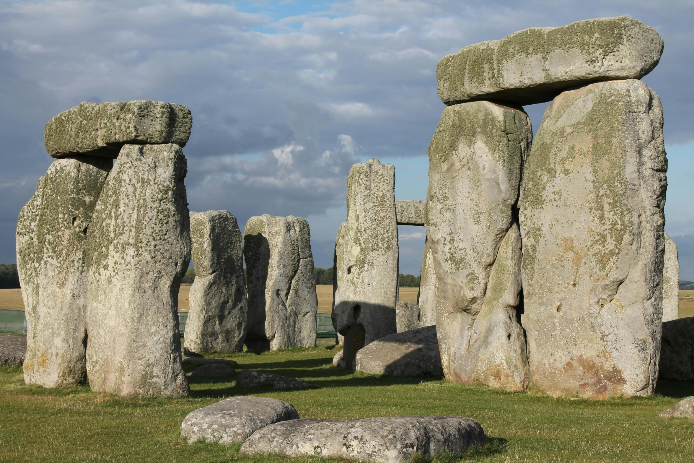 a group of large rocks sitting on top of a grass covered field, a marble sculpture, stonehenge, wide views, parks and gardens, exterior photo